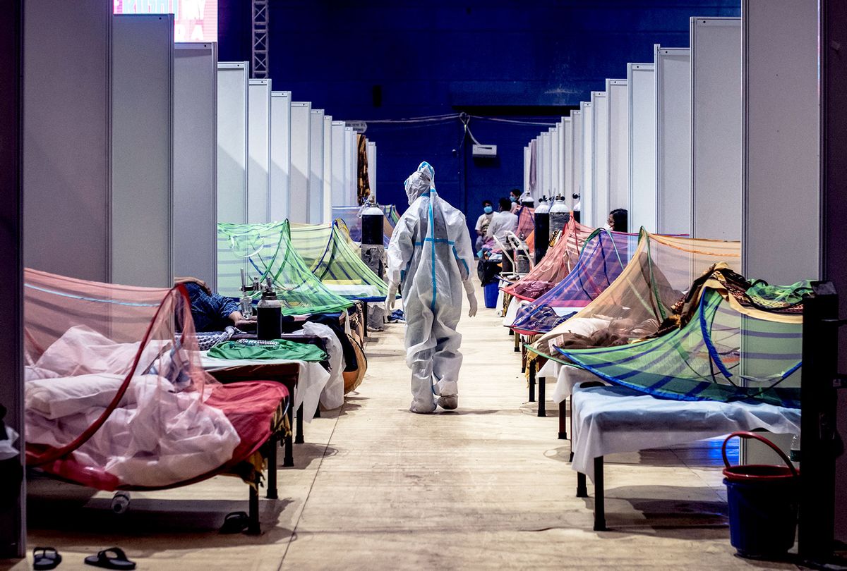 A medical worker in PPE observes patients who have been infected by Covid-19 inside a makeshift covid care facility in a sports stadium at the Commonwealth Games Village in New Delhi, India. (Getty Images/Stringer)