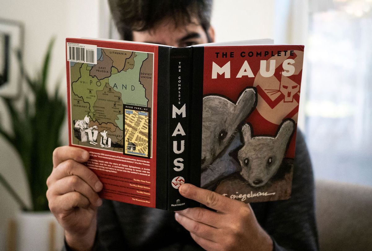 This illustration photo taken in Los Angeles, California on January 27, 2022 shows a person holding the graphic novel "Maus" by Art Spiegelman. A school board in Tennessee has added to a surge in book bans by conservatives with an order to remove the award-winning 1986 graphic novel on the Holocaust, "Maus," from local student libraries. Author Art Spiegelman told CNN on January 27 -- coincidentally International Holocaust Remembrance Day -- that the ban of his book for crude language was "myopic" and represents a "bigger and stupider" problem than any with his specific work. (MARO SIRANOSIAN/AFP via Getty Images)