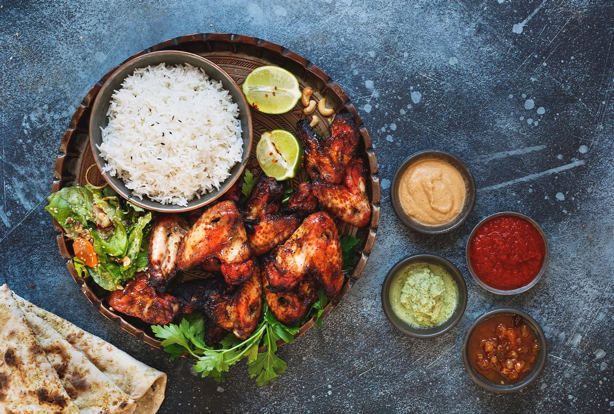 Tandoori chicken wings served with pilau rice, soft garlic cheese naan with different chutney dipping sauces (Getty Images/SStajic)