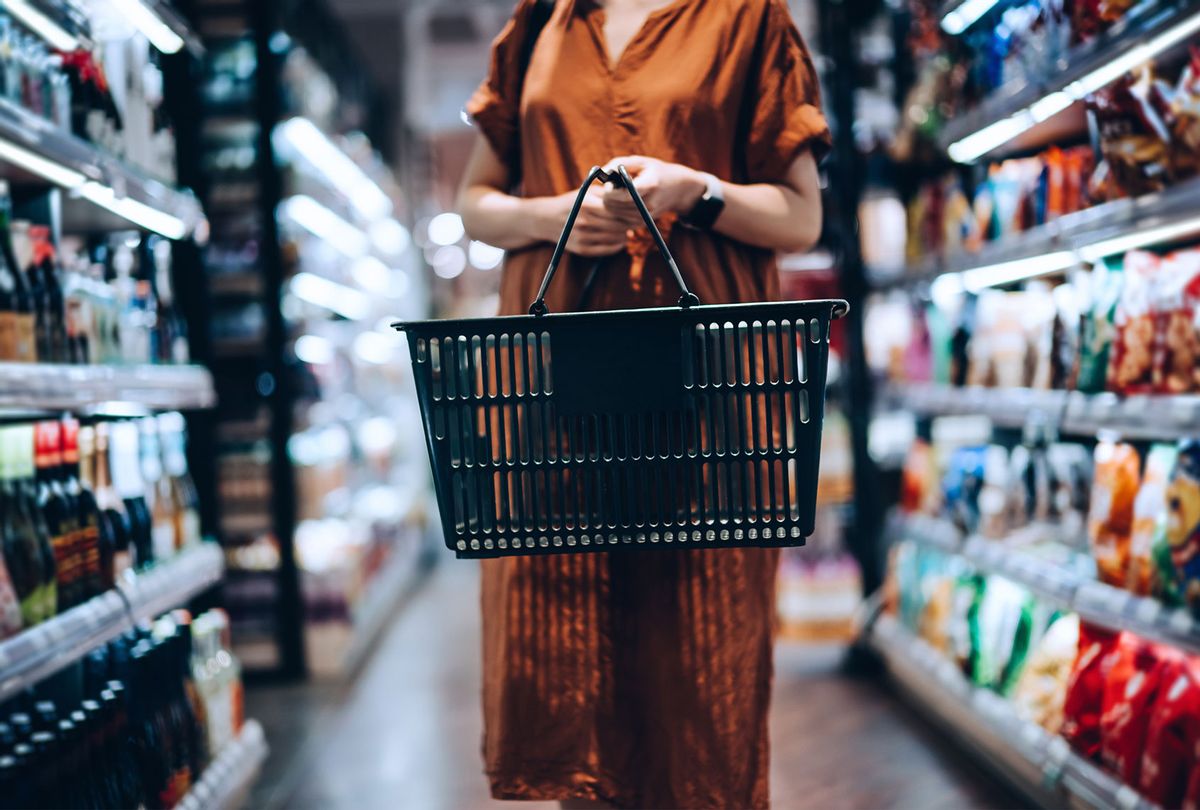 A young woman carrying a shopping basket, standing along the product aisle (Getty Images/d3sign)