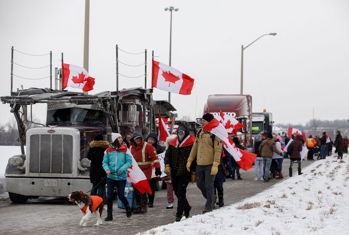 Supporters for a convoy of truckers driving from British Columbia to Ottawa in protest of a Covid-19 vaccine mandate for cross-border truckers, gather near a highway overpass outside of Toronto, Ontario, Canada, on January 27, 2022. - A convoy of truckers started off from Vancouver on January 23, 2022 on its way to protest against the mandate in the capital city of Ottawa. (COLE BURSTON/AFP via Getty Images)