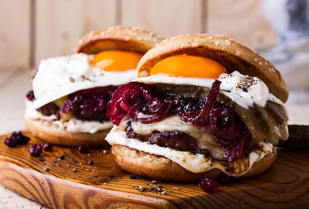Cheeseburger with caramelized onions, fried egg and aioli on rustic cutting board (Getty Images/istetiana)