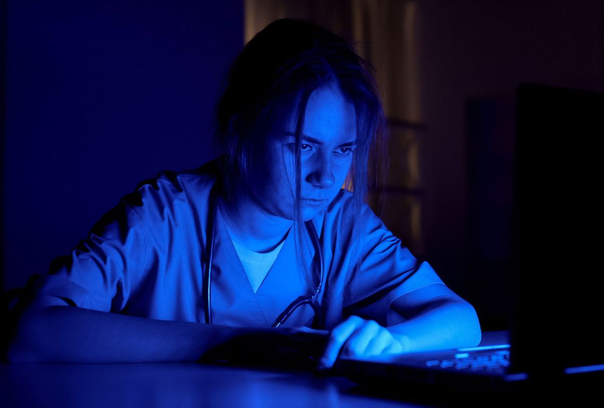 Sleepy nurse on duty sitting in dark room, exhausted by extra work in hospital (Getty Images/Motortion)