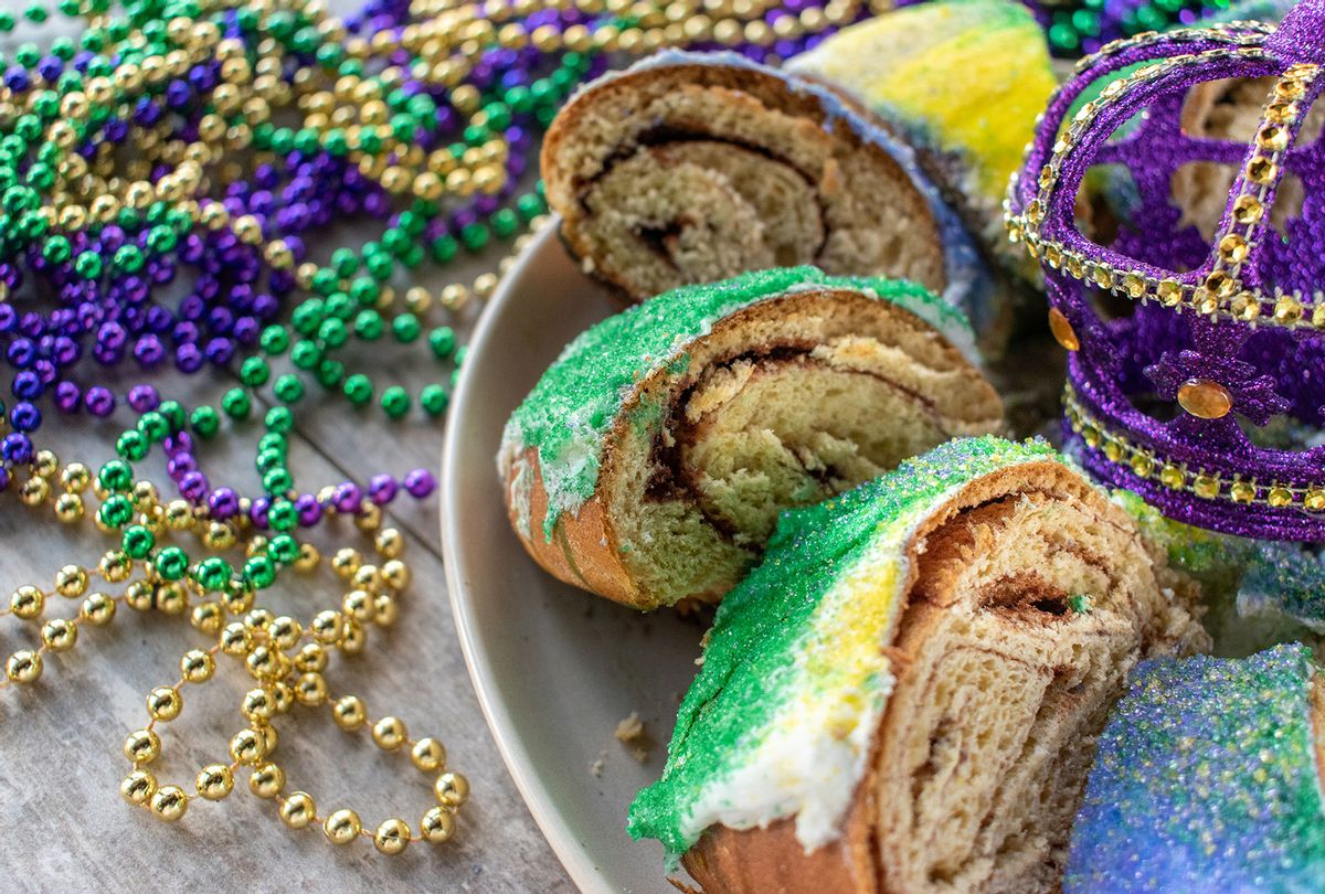 Sliced Mardi Gras King Cake surrounded by colorful beads (Getty Images/Lynne Mitchell)