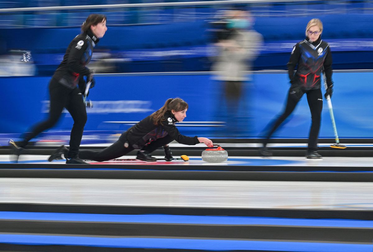 Russia's Olympic Committee Alina Kovaleva curls the stone as Galina Arsenkina and Ekaterina Kuzmina watch during the Beijing 2022 Winter Olympic Games curling competition on February 17, 2022. (LILLIAN SUWANRUMPHA/AFP via Getty Images)