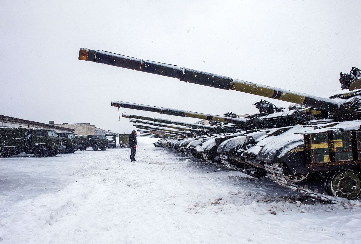 An Ukrainian Military Forces serviceman stands in front of tanks of the 92nd separate mechanized brigade of Ukrainian Armed Forces, parked in their base near Klugino-Bashkirivka village, in the Kharkiv region on January 31, 2022. - The tanks have to restore their combat capability after completing a combat mission in war-torn eastern Ukraine. (SERGEY BOBOK/AFP via Getty Images)