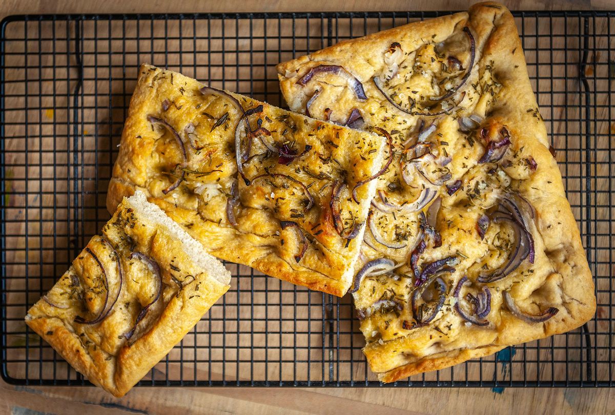 Freshly baked focaccia bread with a rosemary and red onion topping, cooling on a wire rack (Getty images/Ian Laker Photography)