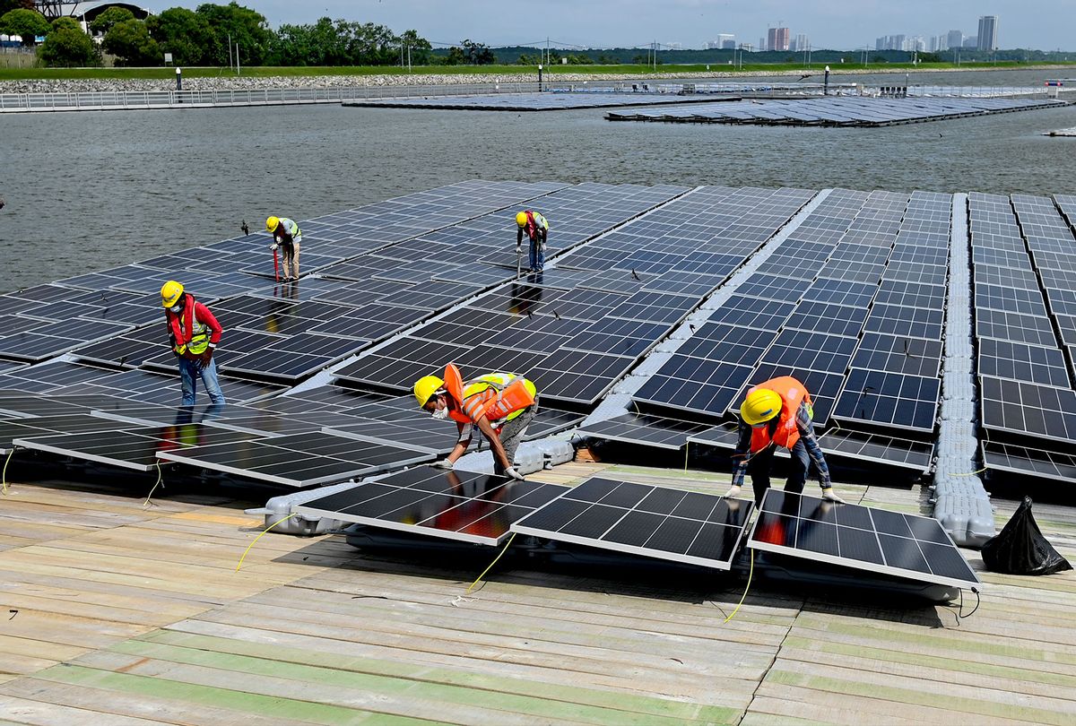This photograph taken on February 3, 2021 shows workers assembling solar panels on the shore of the Tengeh reservoir as part of the constuction of a floating solar power farm in Singapore. (ROSLAN RAHMAN/AFP via Getty Images)