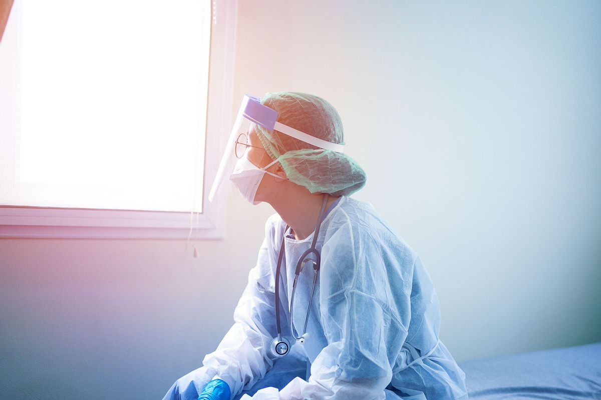 Doctor wearing PPE looking out the window (Getty Images/skaman306)