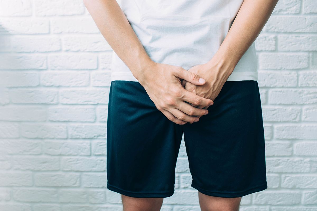 Man wearing shorts holding genitals (Getty Images/peakSTOCK)