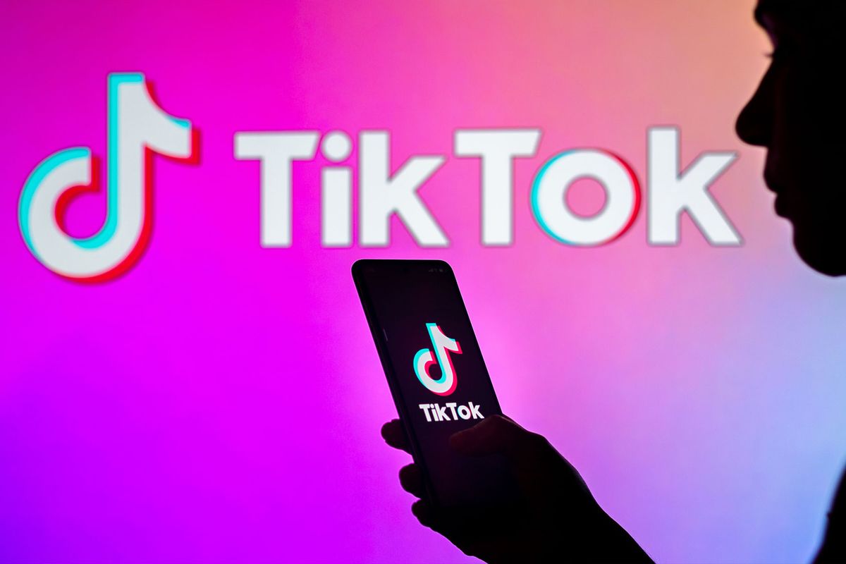 In this photo illustration, a woman's silhouette holds a smartphone with the TikTok logo displayed on the screen and in the background. (Photo Illustration by Rafael Henrique/SOPA Images/LightRocket via Getty Images)