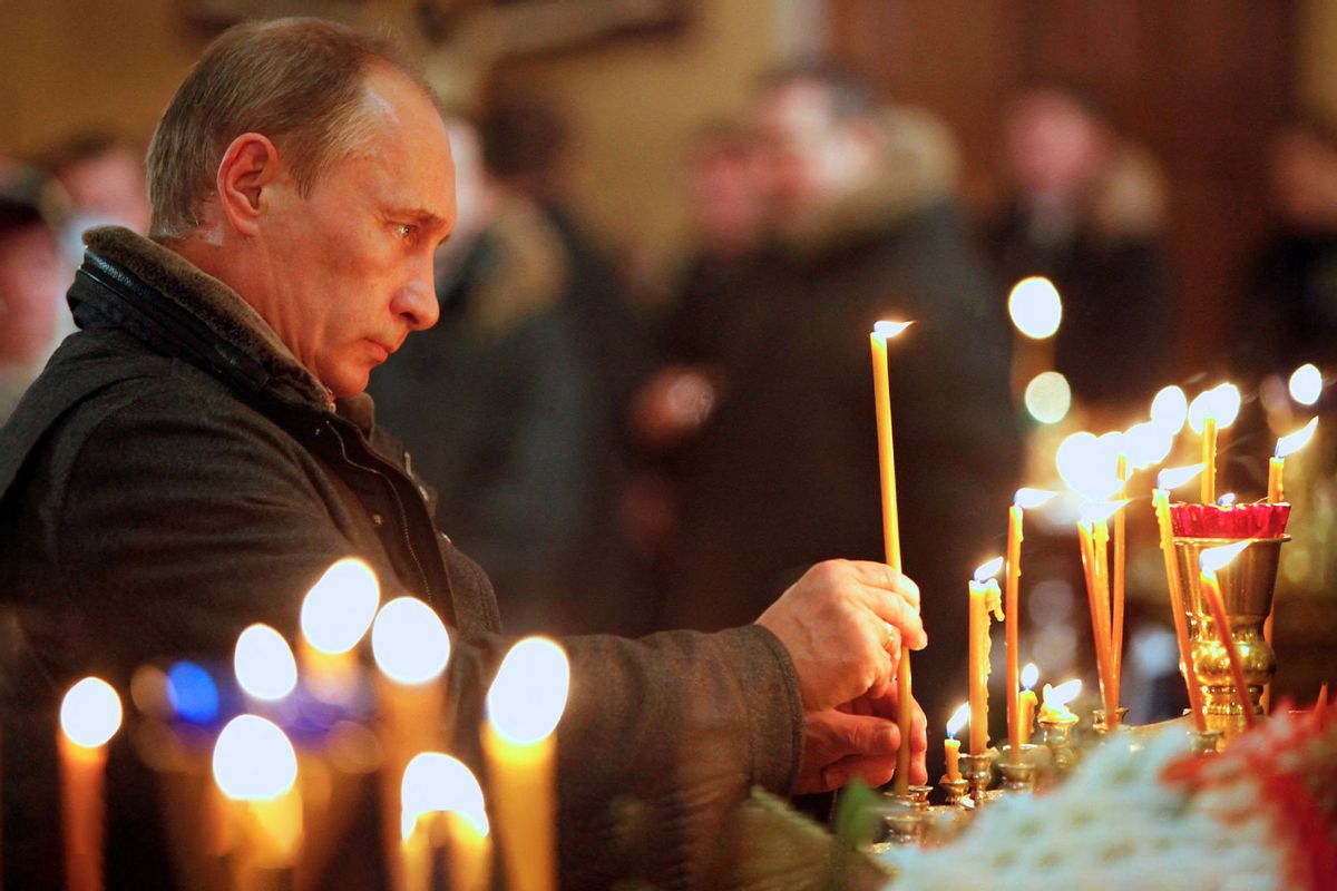 Russian Prime Minister Vladimir Putin lights a candle as he attends an Orthodox Christmas service in the XIX century church of the Protecting Veil of the Mother of God in Turginovo village, about 160 km northwest of Moscow, on January 7, 2011. (ALEXANDER ZEMLIANICHENKO/POOL/AFP via Getty Images)