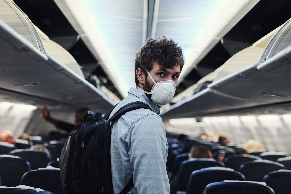 Shot of a young man wearing a mask and boarding an airplane (Getty Images/Adene Sanchez)
