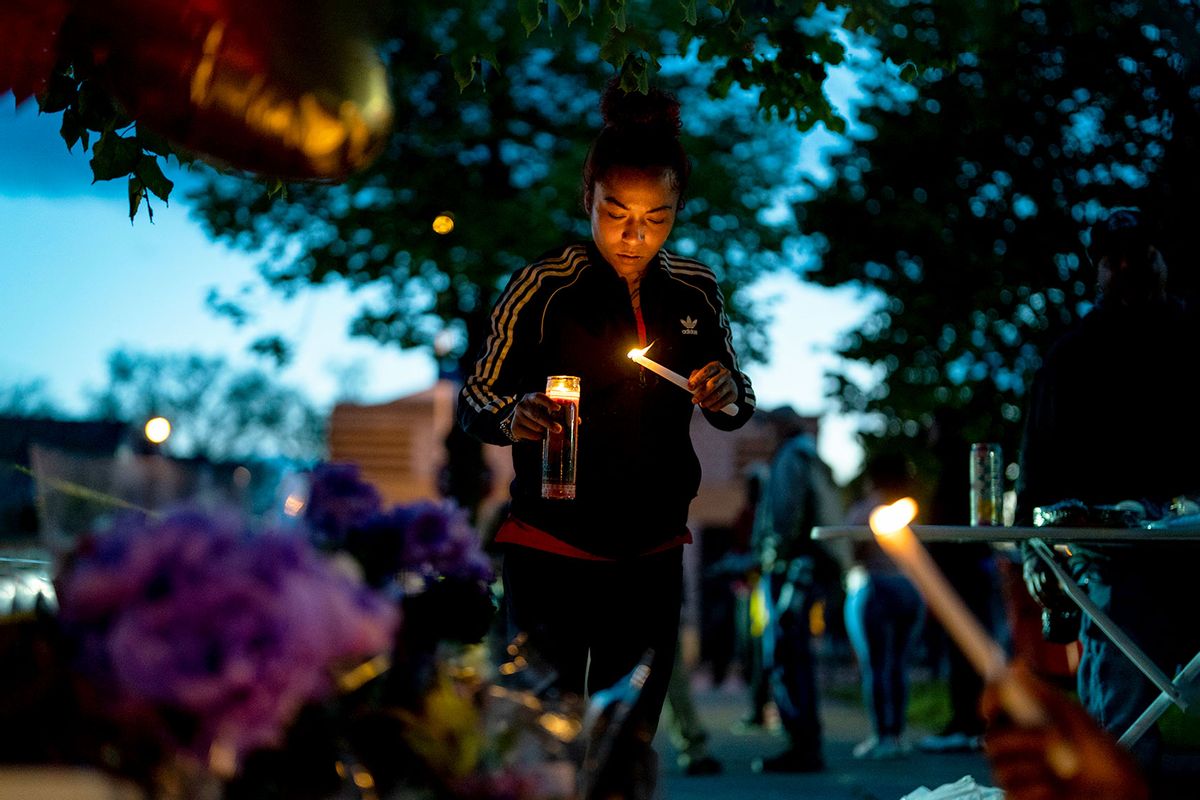 Alexis Rodriguez, of Buffalo, lights candles as people gather at the scene of a mass shooting at Tops Friendly Market at Jefferson Avenue and Riley Street on Monday, May 16, 2022 in Buffalo, NY. (Kent Nishimura / Los Angeles Times via Getty Images)