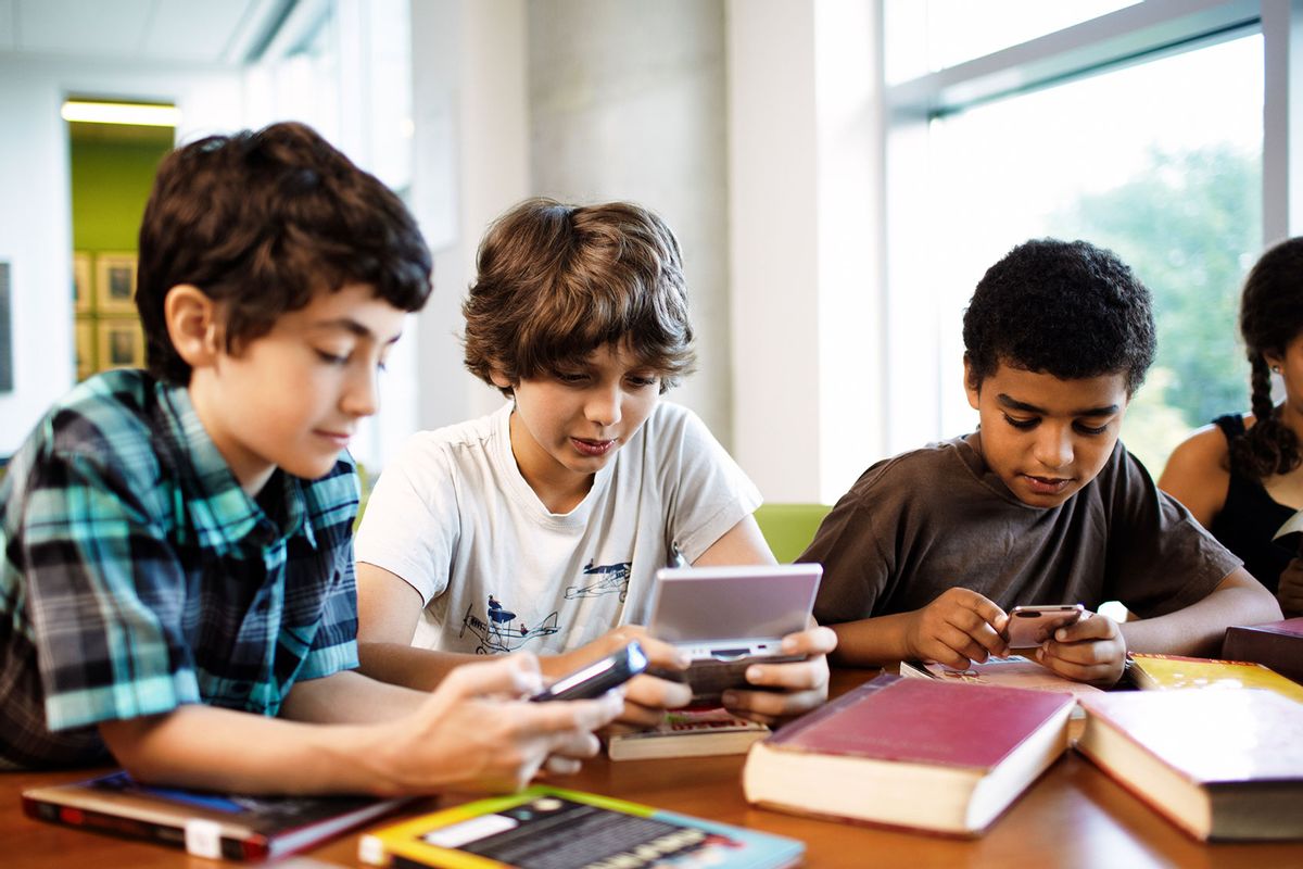 Kids playing with handheld video games in the library (Getty Images/Andy Ryan)