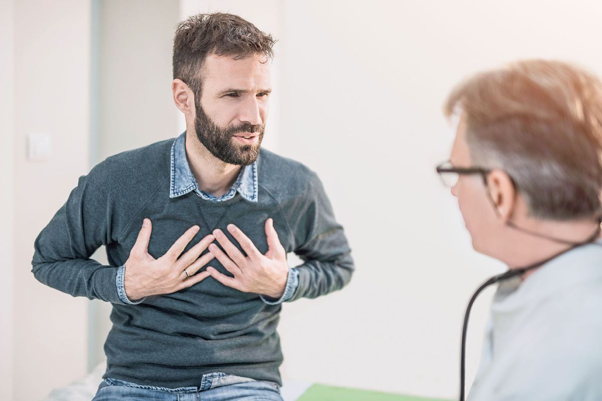 Adult male patient describing a chest issue to his doctor (Getty Images/DjelicS)