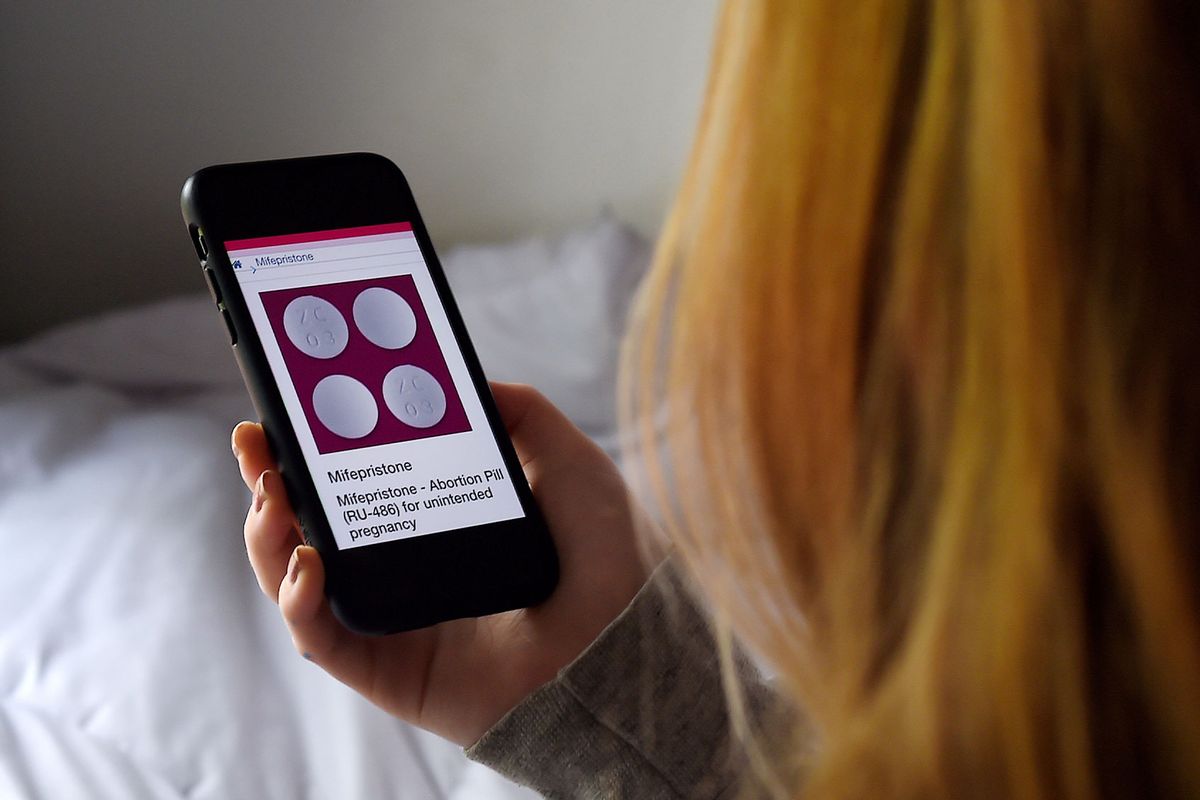 In this photo illustration, a person looks at an Abortion Pill (RU-486) for unintended pregnancy from Mifepristone displayed on a smartphone. (OLIVIER DOULIERY/AFP via Getty Images)