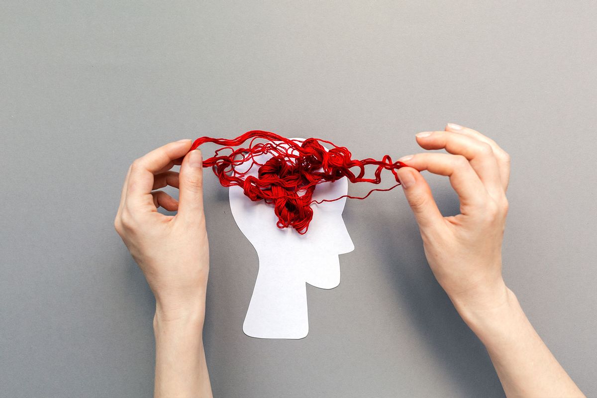 Hands unravel the tangled red threads on the silhouette of the head (Getty Images/Ildar Abulkhanov)