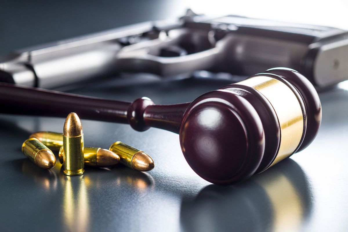 Judge gavel and gun bullets on black table (Getty Images/jirkaejc)