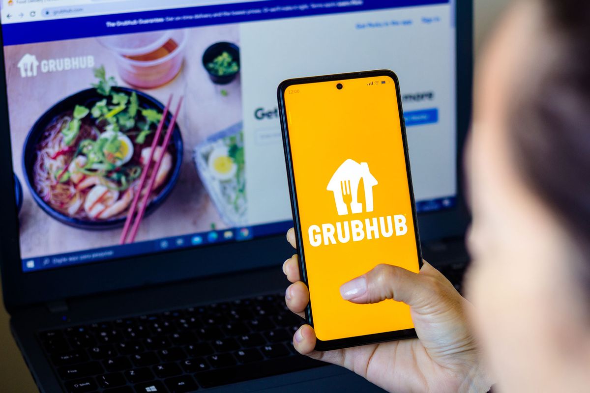 In this photo illustration, a woman holds a smartphone with the Grubhub Inc. logo displayed on the screen with the Grubhub website displayed in the background. (Photo Illustration by Rafael Henrique/SOPA Images/LightRocket via Getty Images)