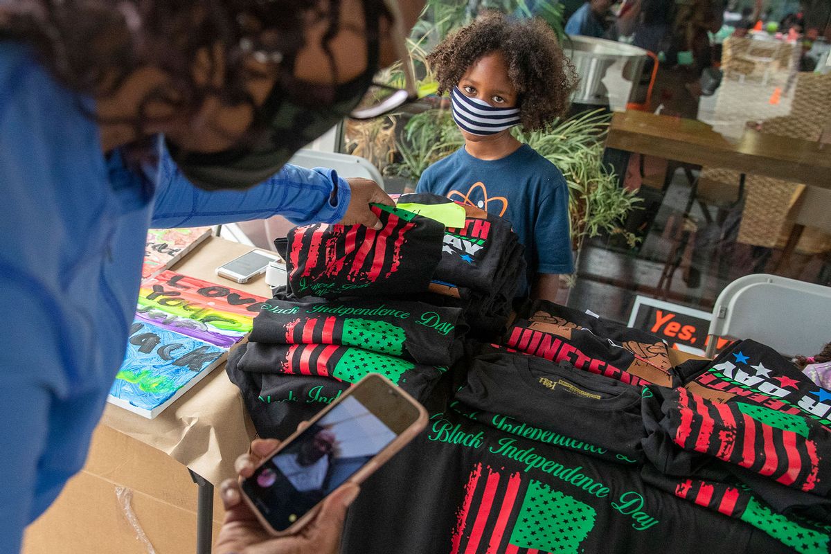 Taj Amin-Jolly sells commemorative t-shirts in from of his parent's cafe during Juneteenth celebration on Friday, June 19, 2020 in Leimert Park, CA. (Brian van der Brug / Los Angeles Times via Getty Images)