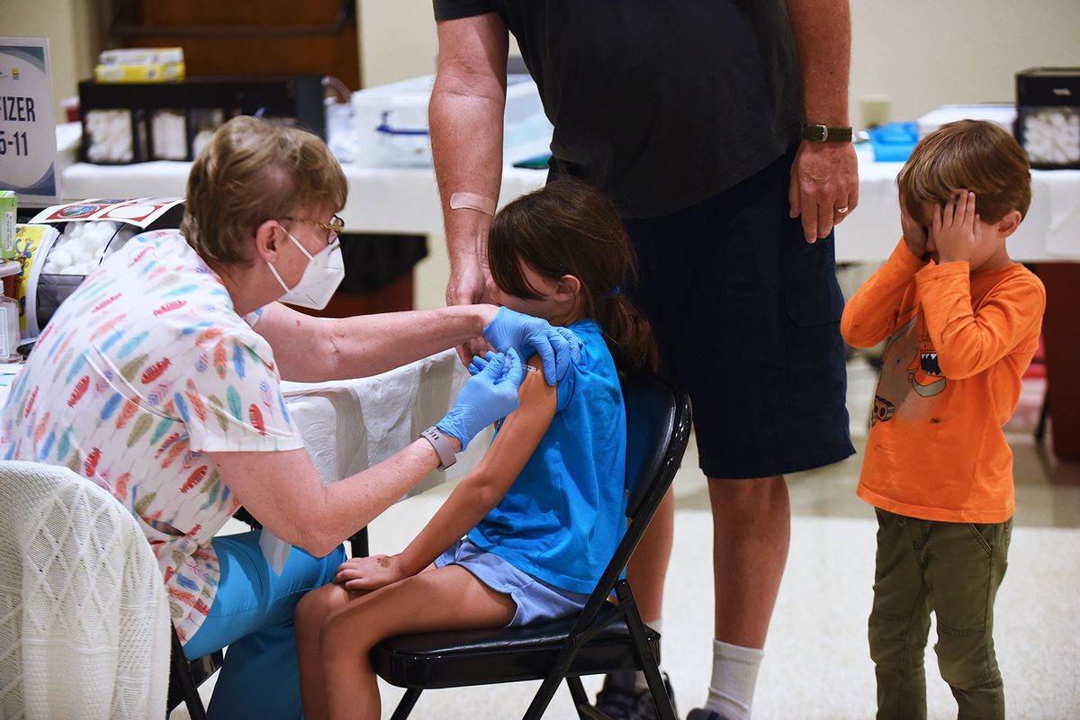 A nurse gives a little girl a shot of the Pfizer COVID-19 vaccine while her brother covers his eyes at a vaccination site for 5-11 year-olds at Eastmonte Park. (Paul Hennessy/SOPA Images/LightRocket via Getty Images)