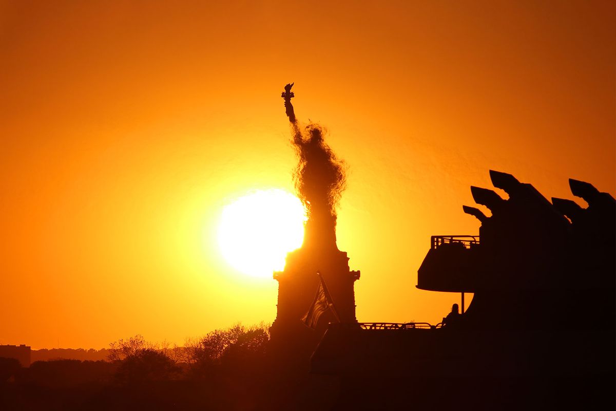 The sun sets behind the Statue of Liberty as it is partially obscured by heat waves from the exhaust of a passing ferry on May 31, 2020, in New York City. (Gary Hershorn/Getty Images)