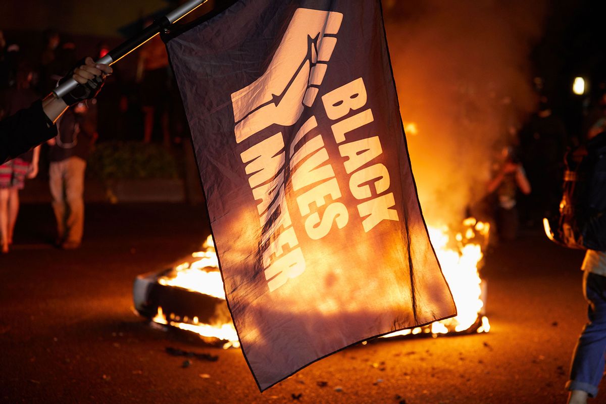 A Black Lives Matter flag waves in front of a fire at the North Precinct Police building in Portland, Oregon on September 6, 2020. - Protestors are marching for an end to racial inequality and police violence. (ALLISON DINNER/AFP via Getty Images)