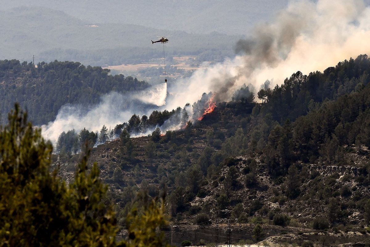 A helicopter drops water over a wildfire near El Pont de Vilomara, in Catalonia, on July 18, 2022. - Emergency services battled several wildfires as Spain remained in the grip of an exceptional heatwave that has seen temperatures reach 43 degrees Celsius (109 degrees Farenheit). (PAU BARRENA/AFP via Getty Images)