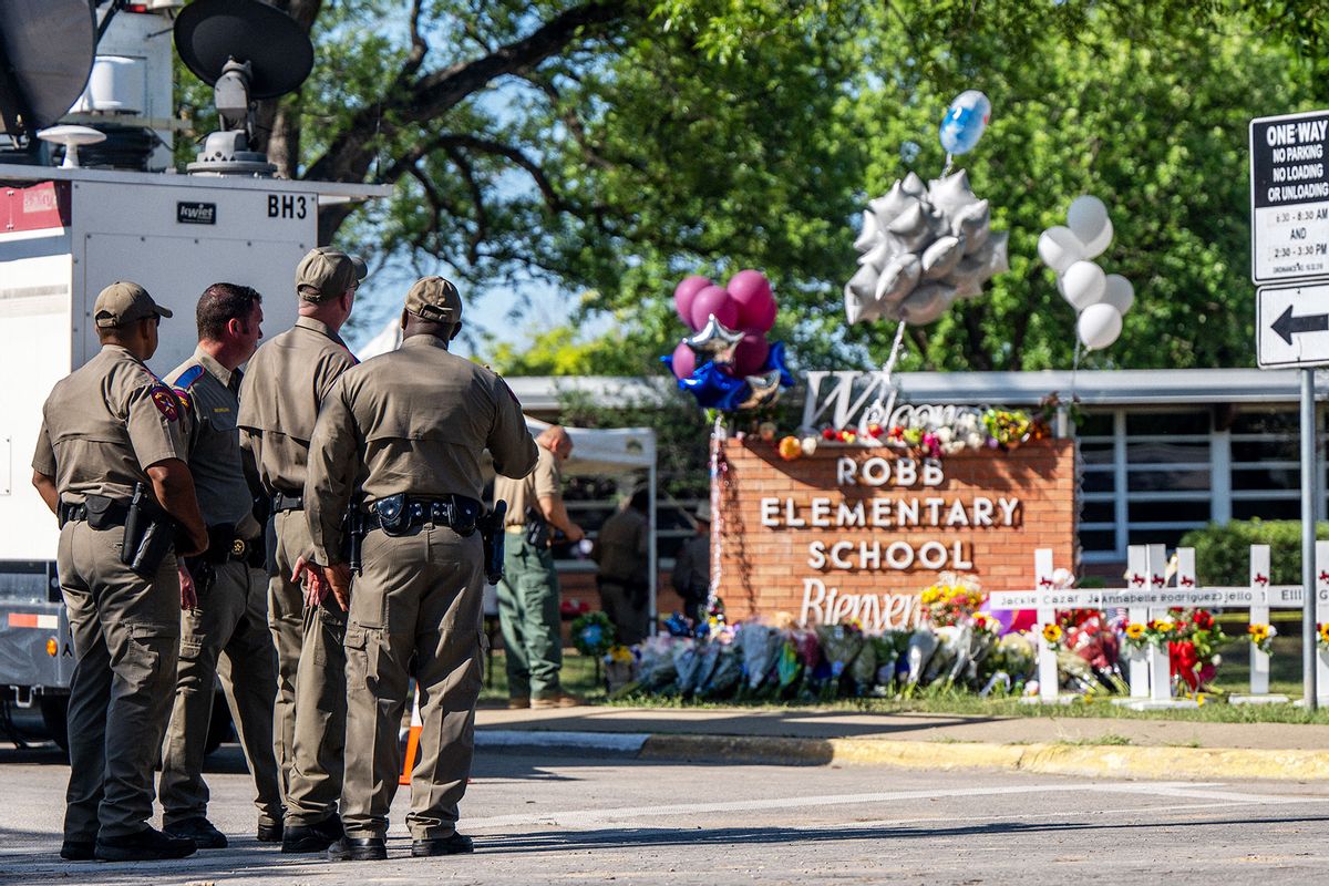Law enforcement officers stand looking at a memorial following a mass shooting at Robb Elementary School on May 26, 2022 in Uvalde, Texas. (Brandon Bell/Getty Images)