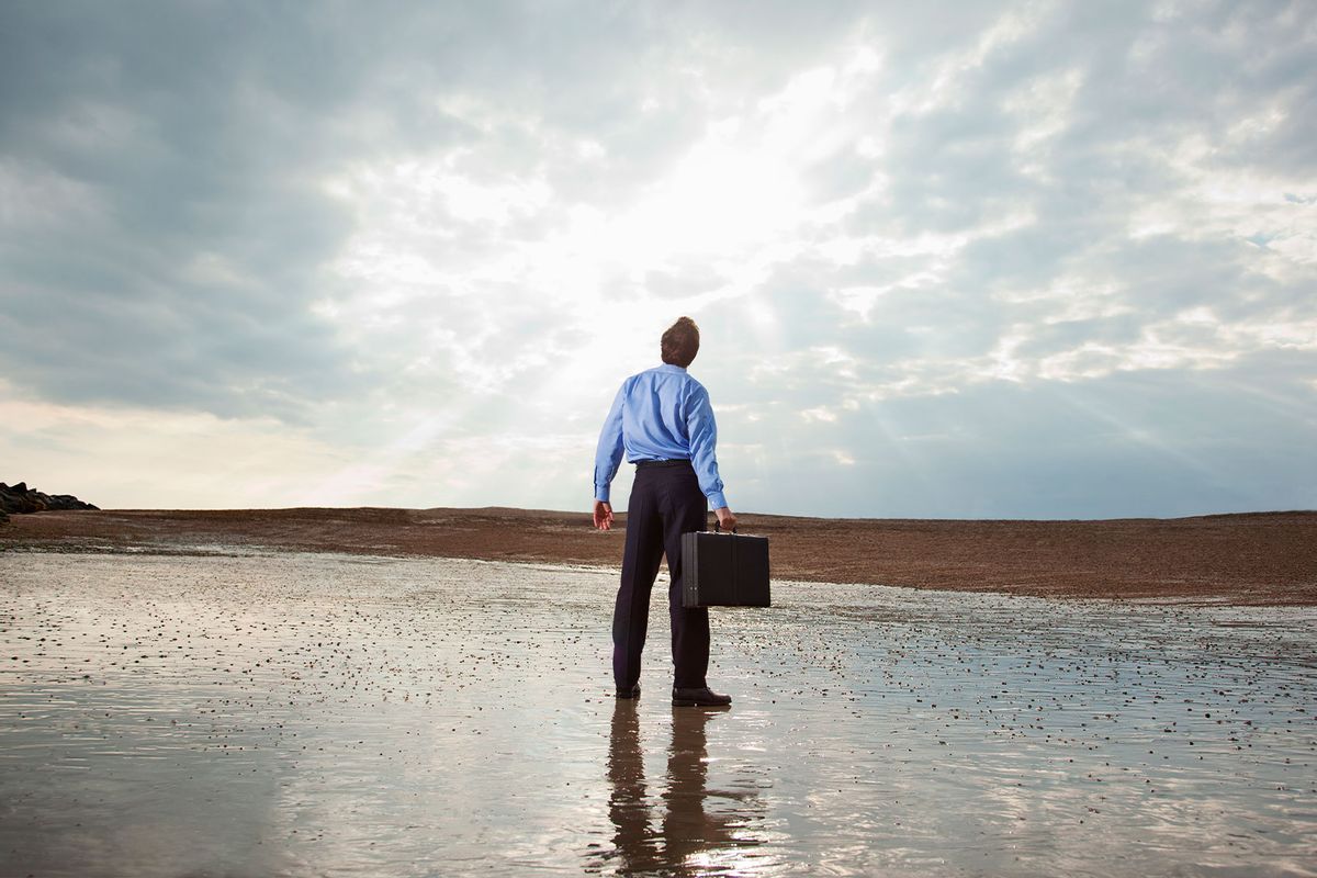 Businessman standing on beach looking at sky (Getty Images/Mark Langridge)