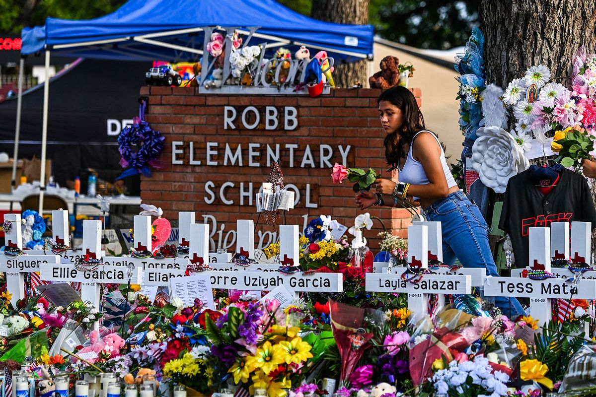 A girl lays flowers at a makeshift memorial at Robb Elementary School in Uvalde, Texas, on May 28, 2022. (CHANDAN KHANNA/AFP via Getty Images)