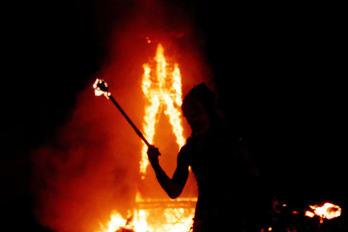 A dancer juggles fire as a 52-foot tall wooden man as it goes up in flames September 2, 2000 during the 15th annual Burning Man festival in the Black Rock Desert near Gerlach, Nevada. (David McNew/Newsmakers/Getty Images)