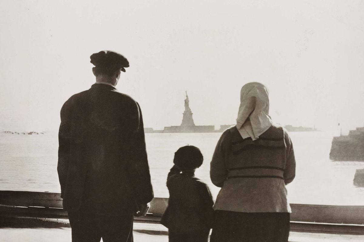 An immigrant family looking at the Statue of Liberty from Ellis Island. circa 1930. (Courtesy of Library of Congress)