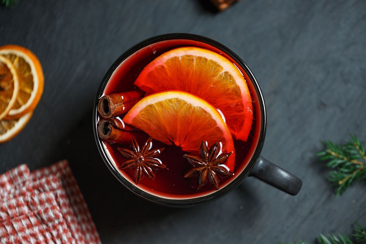Black mug with bright red mulled wine, two slices of orange, cinnamon and star anise (Getty Images/Ignatiev)