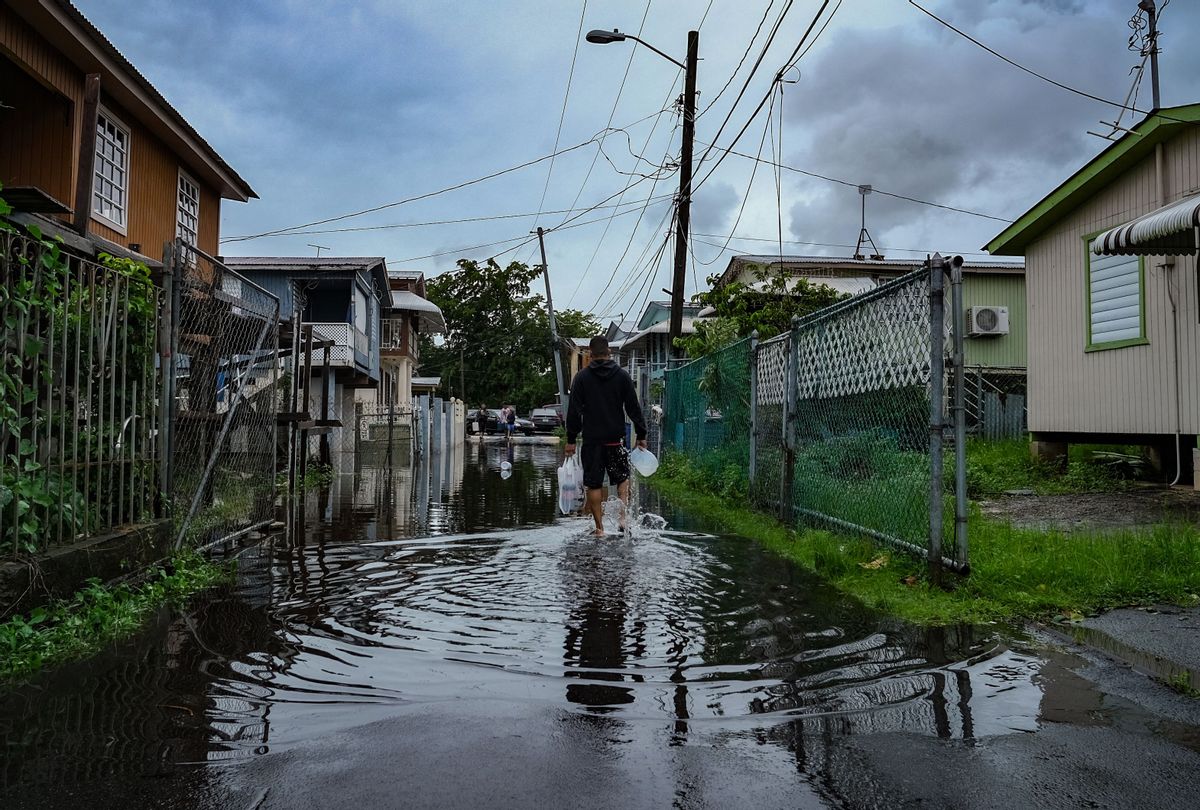 A man walks down a flooded street in the Juana Matos neighborhood of Catano, Puerto Rico, on September 19, 2022, after the passage of Hurricane Fiona. (AFP via Getty Images)