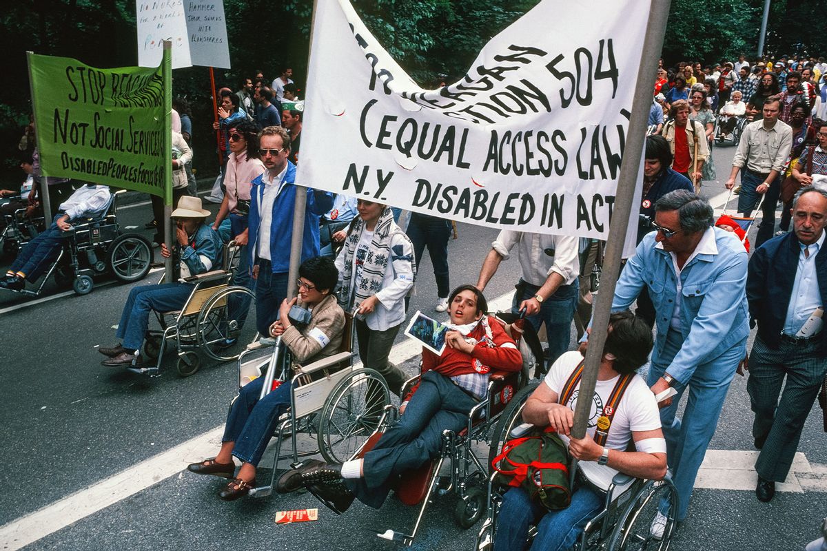 View of demonstrators in wheelchairs in Central Park, many with signs that read 'Stop Reaganism, Not Social Services (and) Jobs' and an another in support of Section 504 of the Rehabilitation Act of 1973, which prohibited discrimination against people disabilities and which was, at the time, under threat from the Reagan administration, in New York, New York, July 12, 1982 (Leif Skoogfors/Getty Images)