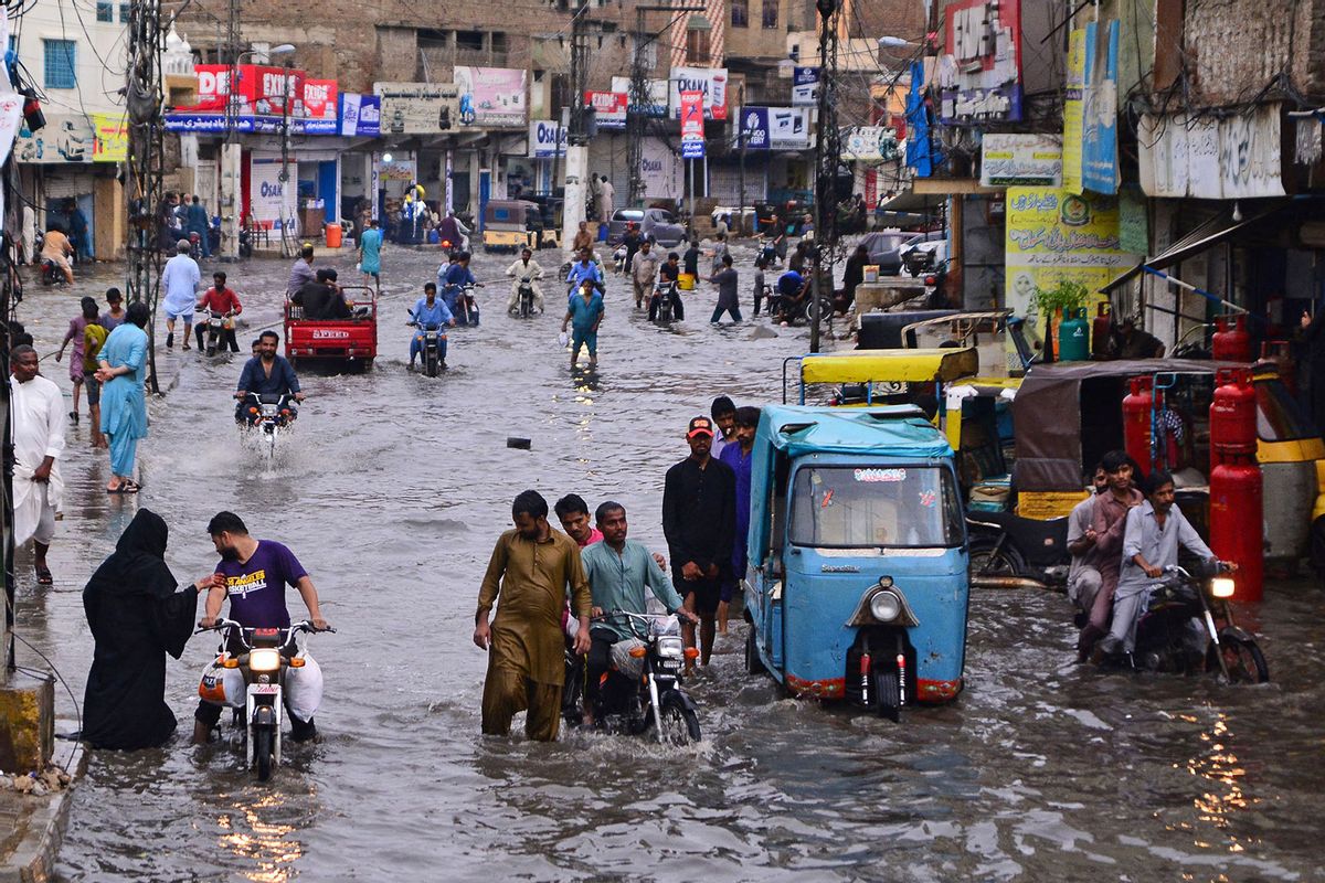 Commuters make their way through a flooded street during monsoon rainfall in Hyderabad on July 24, 2022. (AKRAM SHAHID/AFP via Getty Images)