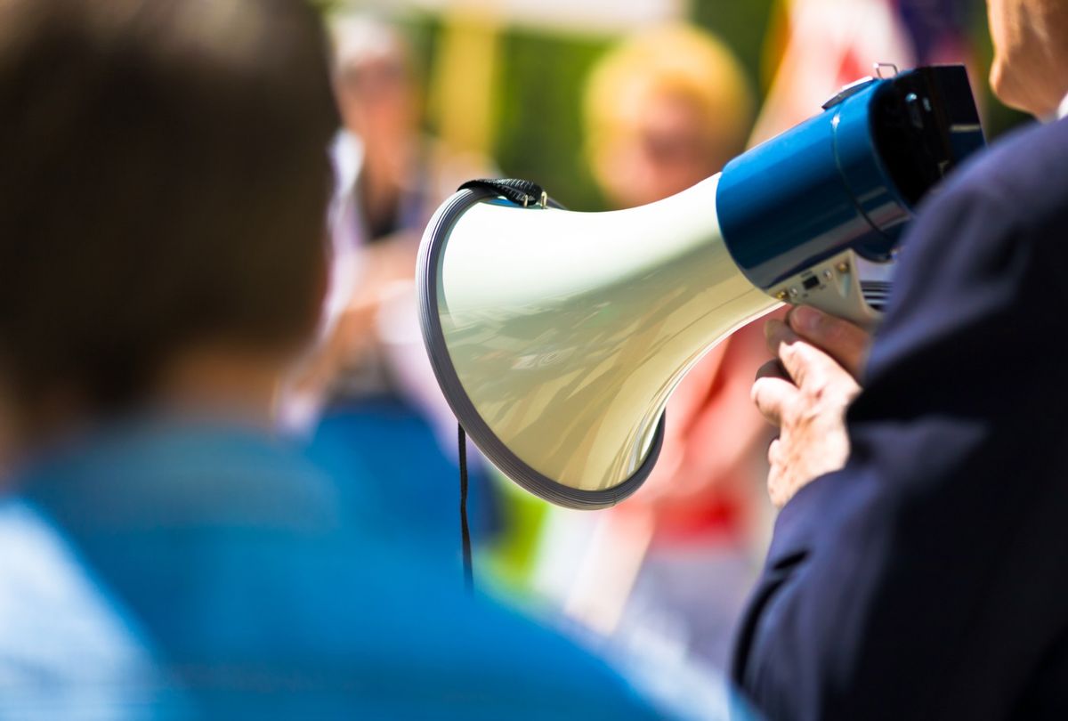 Man holding a megaphone while speaking to a crowd. (slobo/Getty Images)
