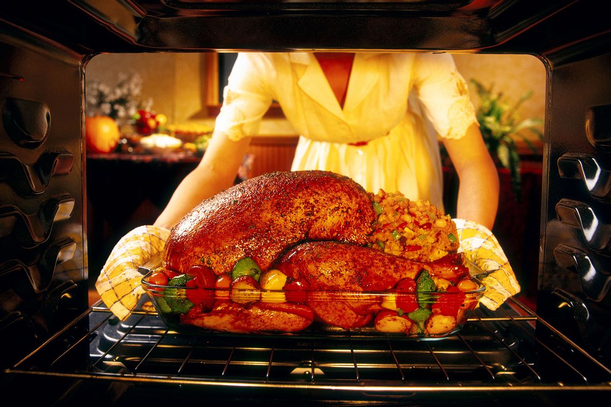 Woman preparing roasted turkey in oven (Getty Images/Lew Robertson)