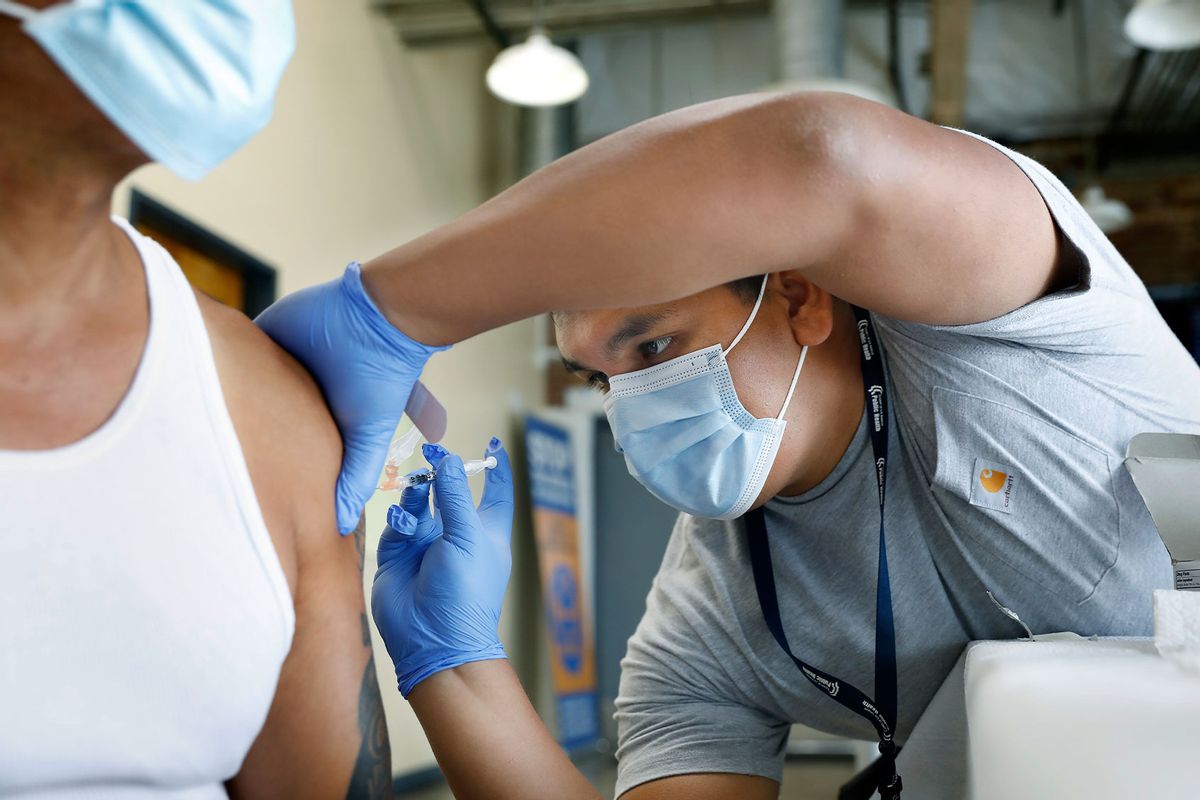 A registered nurse with The Los Angeles Department of Public Health, administers a COVID booster at a vaccination clinic (Christina House / Los Angeles Times via Getty Images)