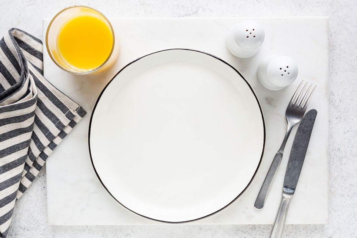 Empty plate, cutlery, orange juice and salt and pepper shaker table setting (Getty Images/Arx0nt)