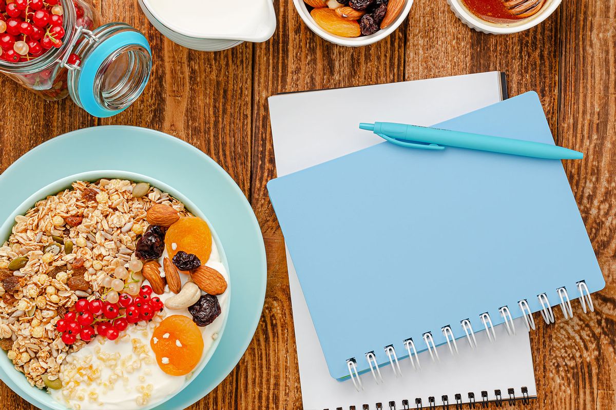 Notebook for diet plan and granola bowl with fruits (Getty Images/Serhii Tychynskyi)