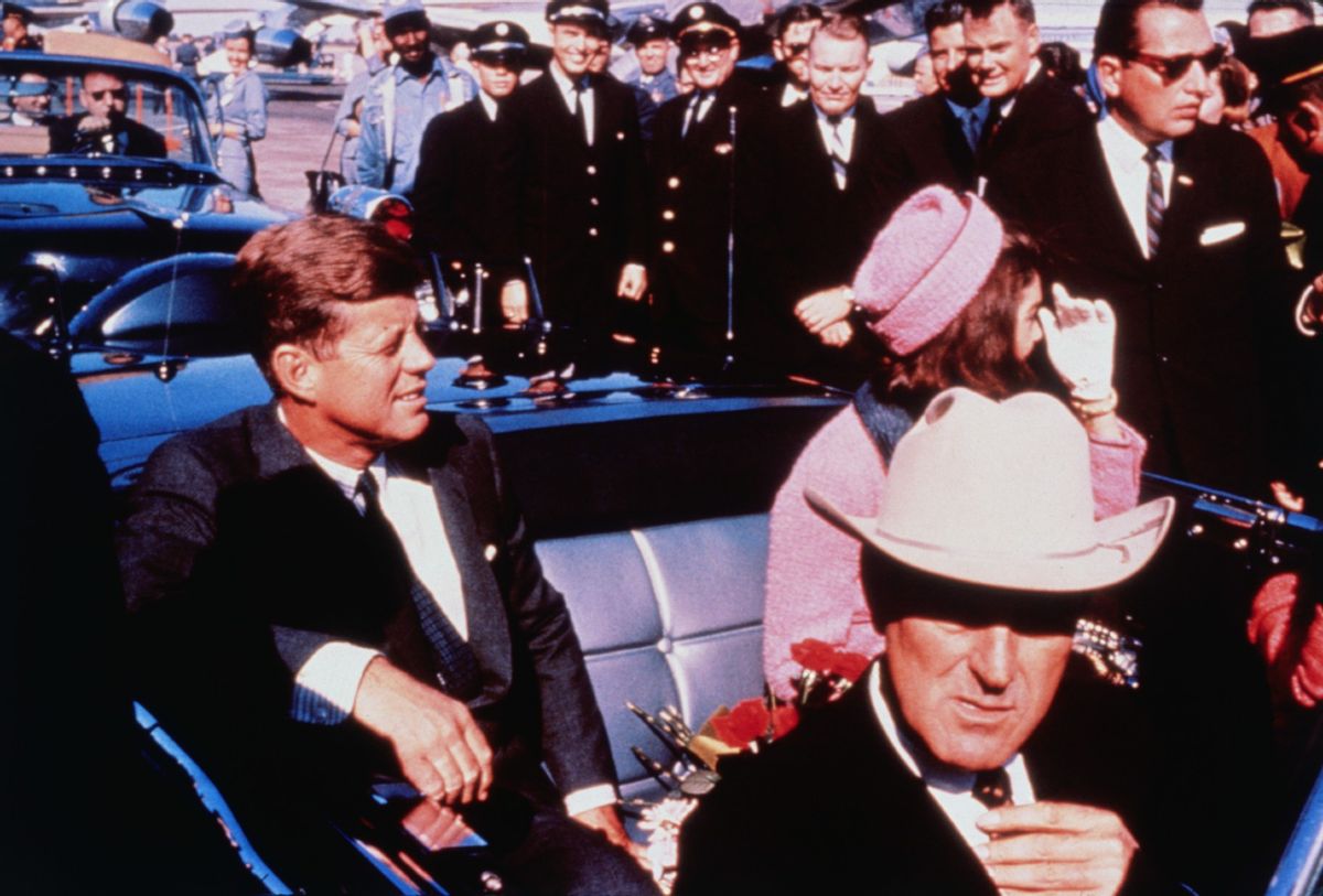 Texas Governor John Connally adjusts his tie (foreground) as US President John F Kennedy (left) & First Lady Jacqueline Kennedy (in pink) settled in rear seats, prepared for motorcade into city from airport, Nov. 22. After a few speaking stops, the President was assassinated in the same car.  (Bettmann / Contributor/Getty)