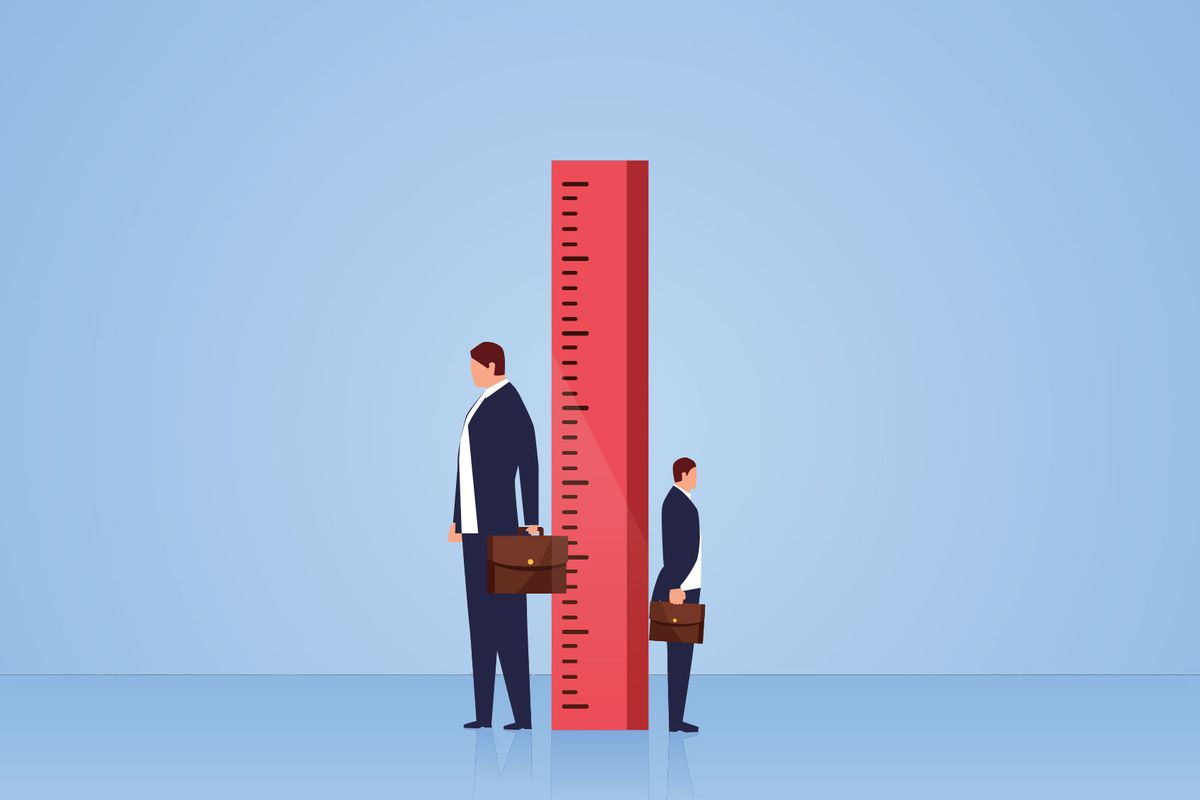 Measuring, two businessmen stand sideways on both sides of the ruler (Getty Images/z_wei)