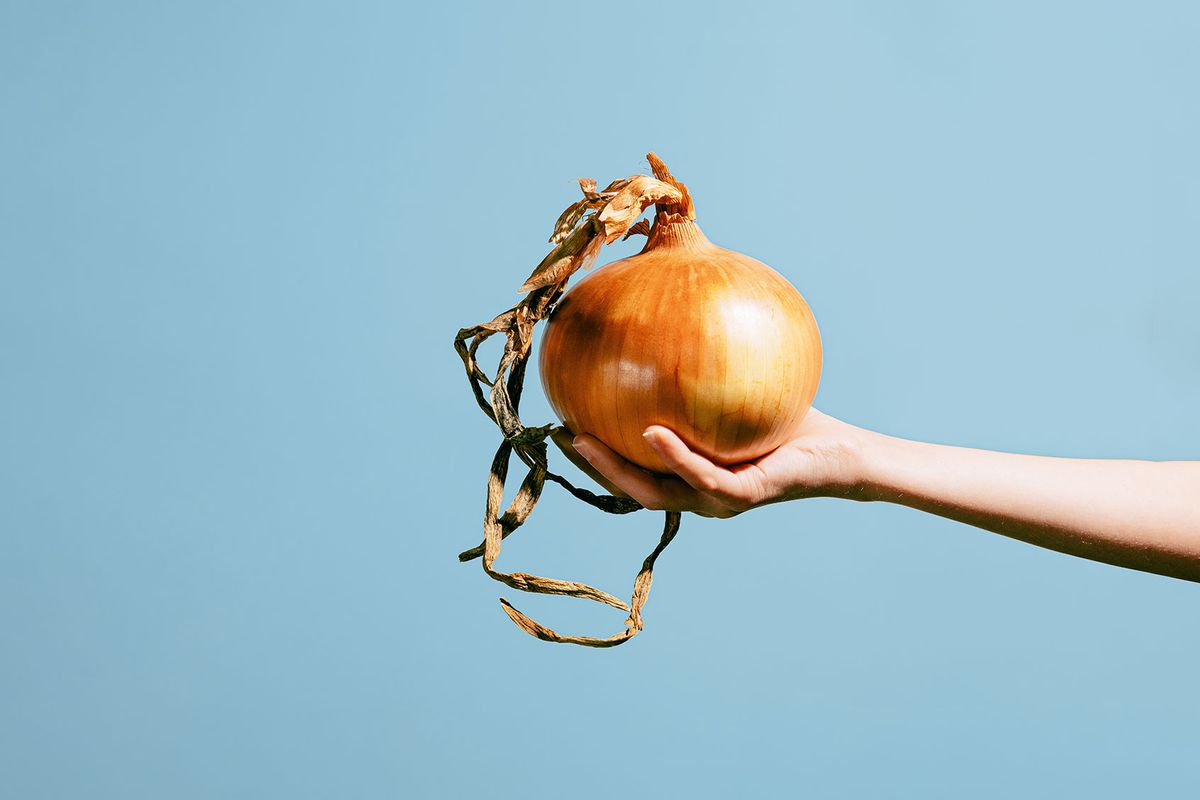 Hand holding a giant onion (Getty Images/Israel Sebastian)