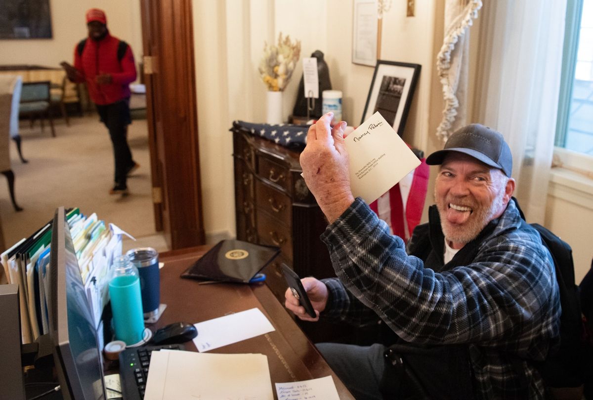 Richard Barnett, a supporter of US President Donald Trump, holds a piece of mail as he sits inside the office of US Speaker of the House Nancy Pelosi after protestors breached the US Capitol in the US Capitol in Washington, DC, January 6, 2021.  (SAUL LOEB/AFP via Getty Images)