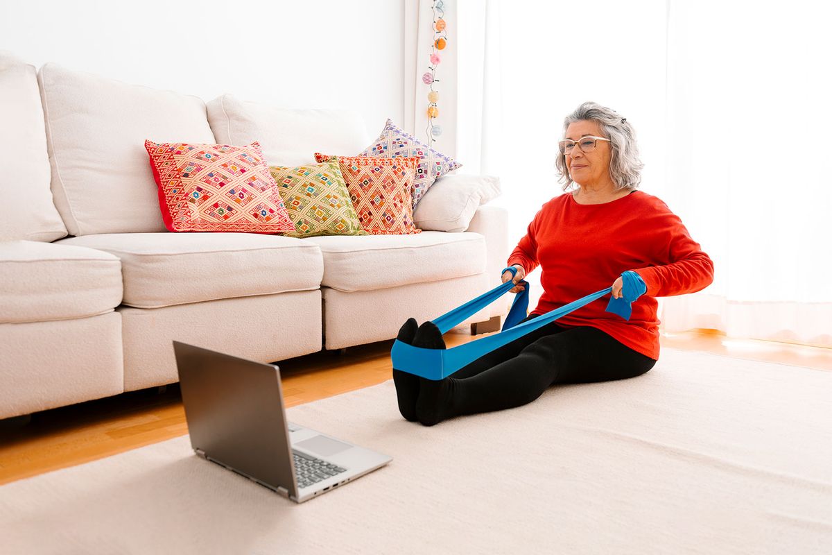 Woman doing home workout while watching tutorial on laptop (Getty Images/Westend61)
