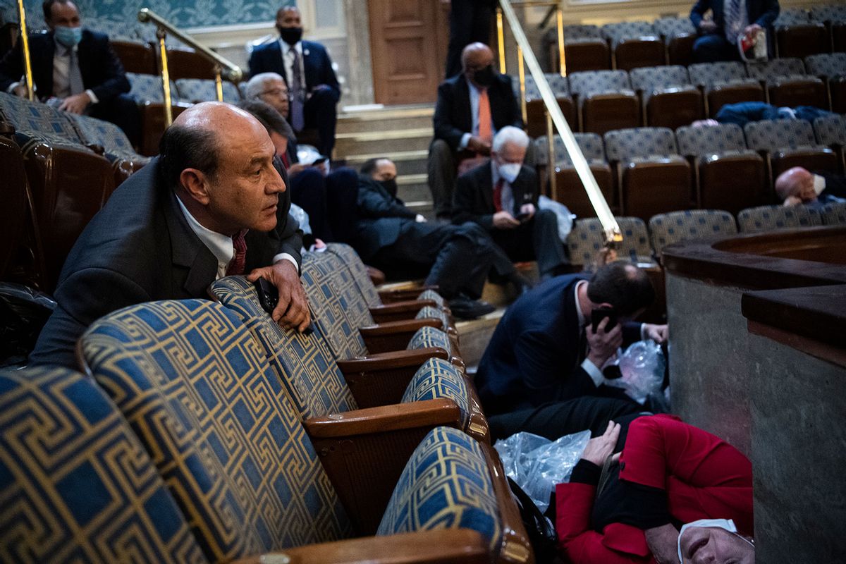 Reps. Lou Correa, D-Calif., left, Susan Wild, D-Pa., and Jason Crow, D-Colo., on phone, take cover as rioters disrupt the joint session of Congress to certify the Electoral College vote in the House chamber of U.S. Capitol on Wednesday, January 6, 2021. (Tom Williams/CQ-Roll Call, Inc via Getty Images)