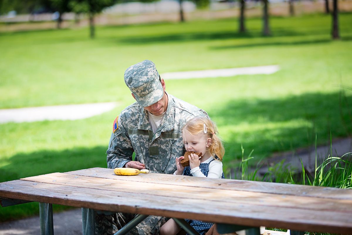 Toddler and American soldier eating lunch together (Getty Images/MivPiv)